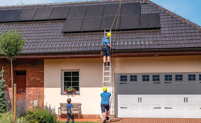 Montáž solárních panelů na střechu rodinného domu pro úsporu energie.