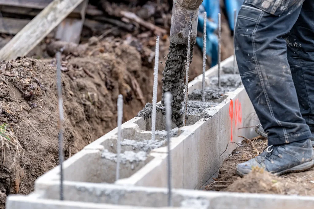 Stavebník nalévá beton do bednění s pruty.