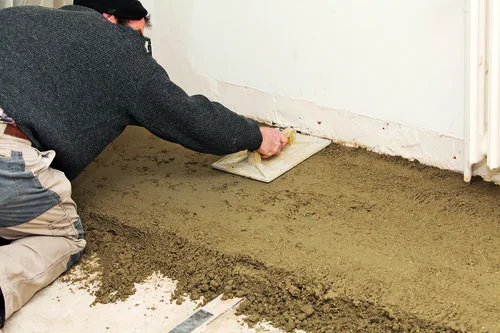 Muž nalévá betonovou podlahu přímo na zem.