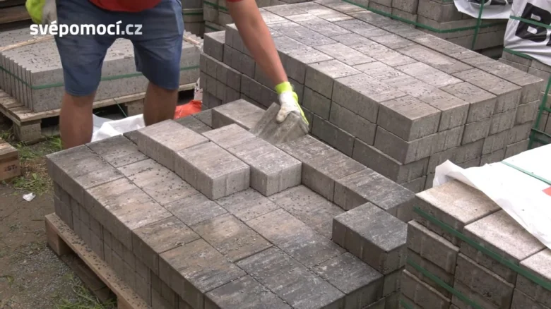 Pracovník pokládá betonové obrubníky na venkově.