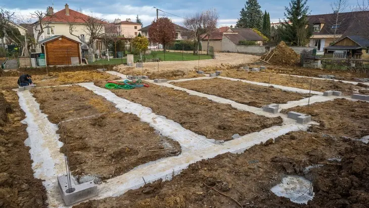 Základy budovy s betonovými pásky na staveništi v okolí domů.