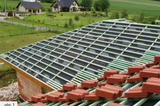 Instalace střešní fólie na skloněnou střechu s červenými taškami.