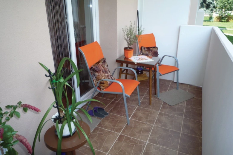 Přestavěná lodžie s oranžovými židlemi a rostlinami.