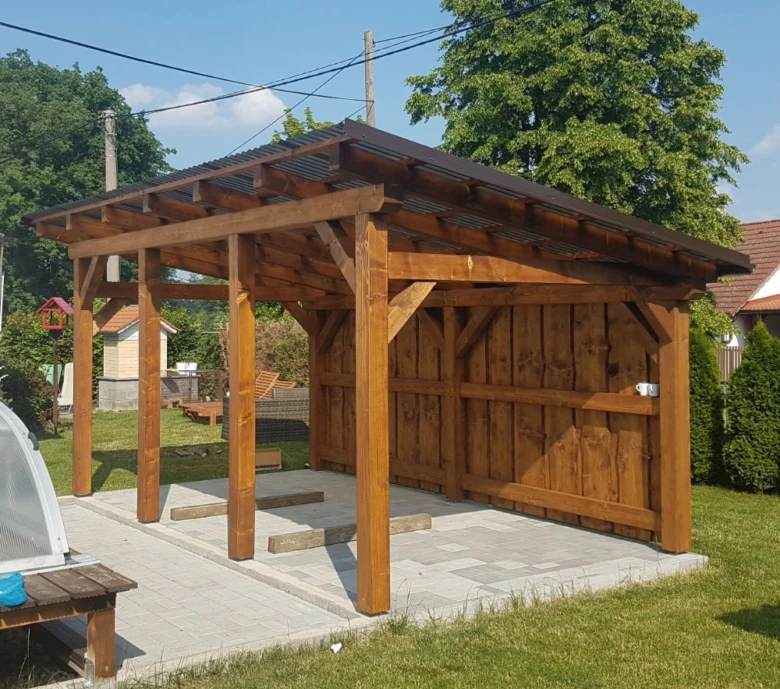 Dřevěná pergola s viditelnými tesařskými spoji v zahradě.