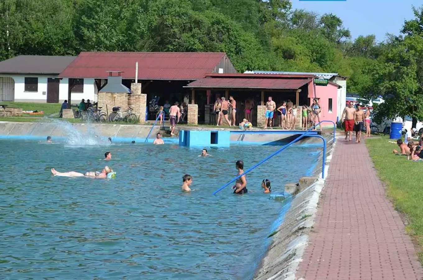 Venkovní bazén ve Všejanech s lidmi v koupacích plavkách.