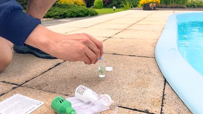 Muž testuje kvalitu vody v bazénu pomocí chemických prostředků.