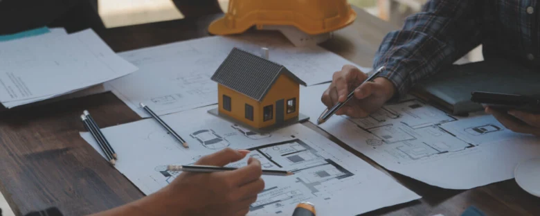 Architektonický model domu s plánem na stavební dokumentaci.