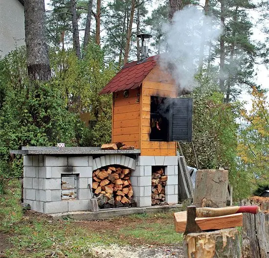 Hotová zděná udírna s dřevem v zásobníku