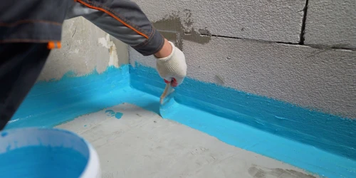 Nápis hydroizolační barvy na betonovou stěnu v koupelně.