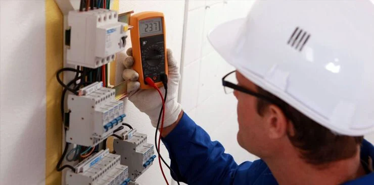 Elektrikář měří napětí v rozvaděči multimetrem při revizi.