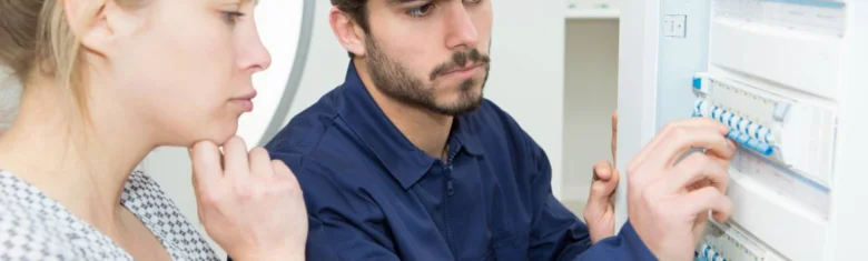 Elektrikář upravuje jističe v rozvaděči před zákazníkem.