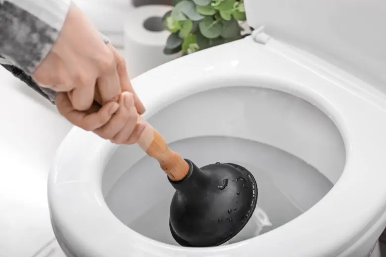 Ruka s hadicí uvolňuje ucpaný záchod.