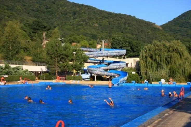 Venkovní bazén s vodními skluzavkami v termálním koupališti.