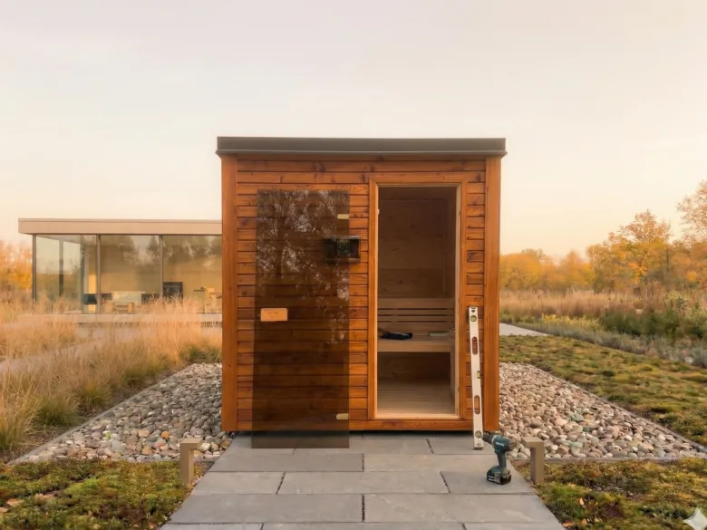 Nově postavená dřevěná sauna venku s nářadím na zahradě.