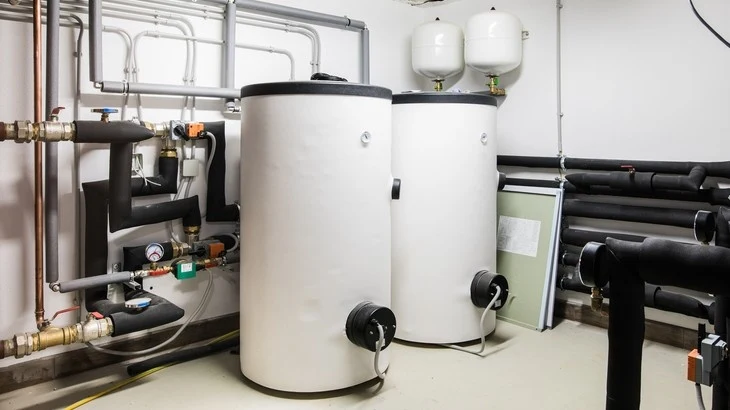 Dvě velké bílé akumulační nádrže na teplou vodu s potrubím.