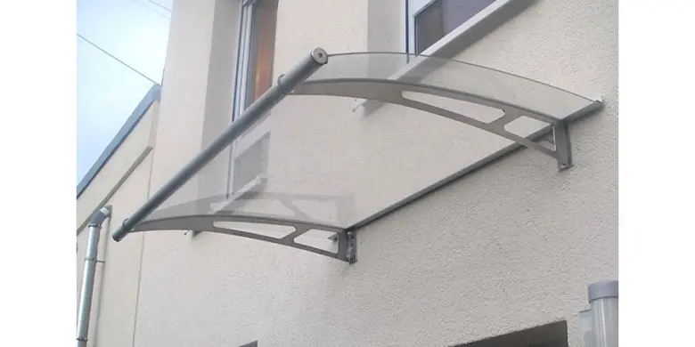Skleněná stříška nad vchodem na fasádě budovy.