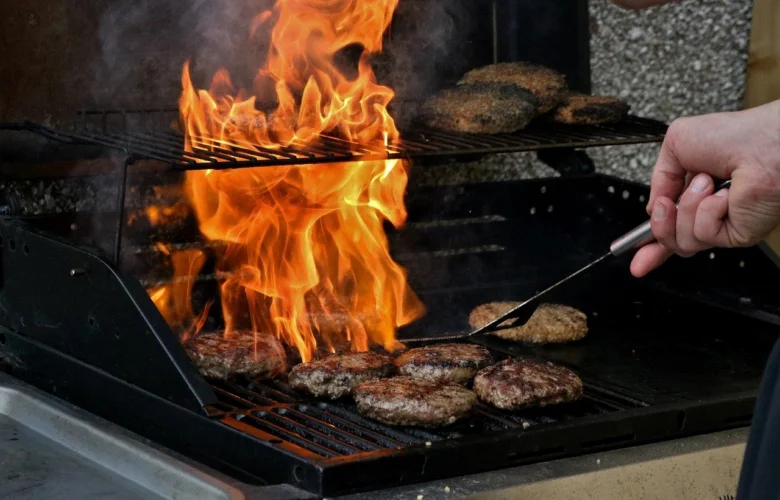 Grilování hamburgerů na zahradním krbu s plameny.