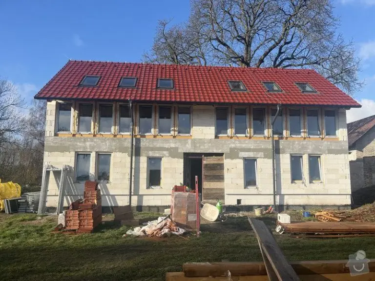 Rodinný dům v hrubé stavbě s červenou střechou.