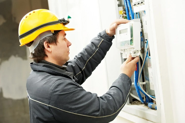 Elektrikář zapojuje elektroměrový rozvaděč v budově.