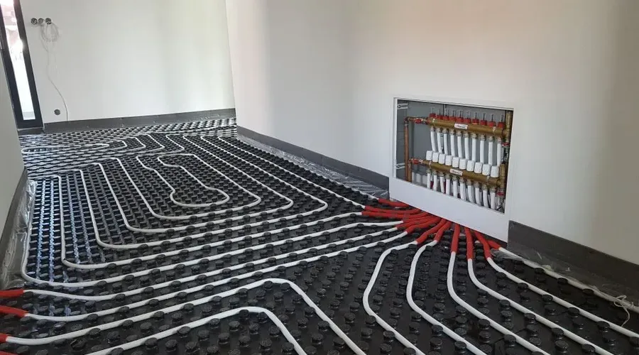 Instalace potrubí podlahového topení s rozdělovačem v zdi.