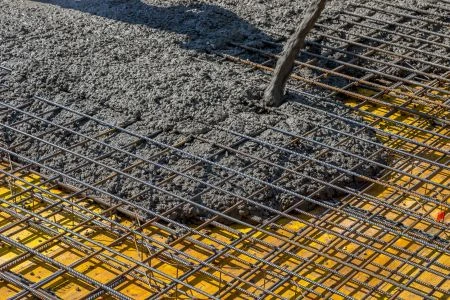 Zalévání betonu na ocelovou výztužnou mřížku ve stavebnictví.