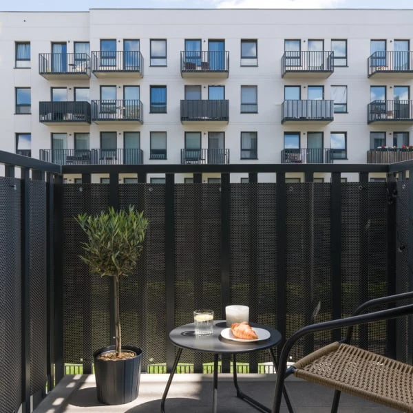 Modernizovaný panelákový balkon s rostlinou a nábytkem.