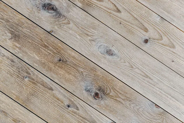 Detail dřevěných prken s viditelnou kresbou a uzly.