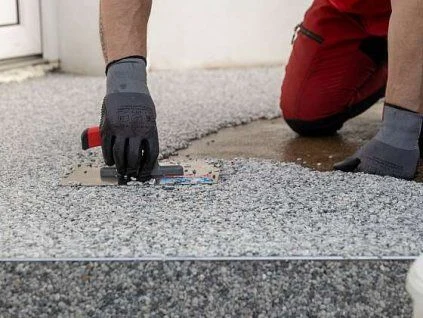 Pracovník nanáší epoxidovou stěrku na betonovou podlahu.