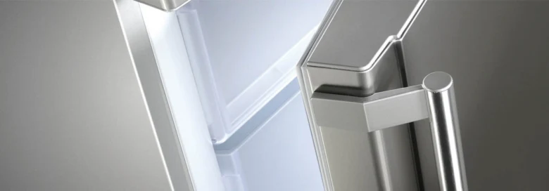 Detailní záběr na nerezovou rukojeť lednice v interiéru kuchyně.