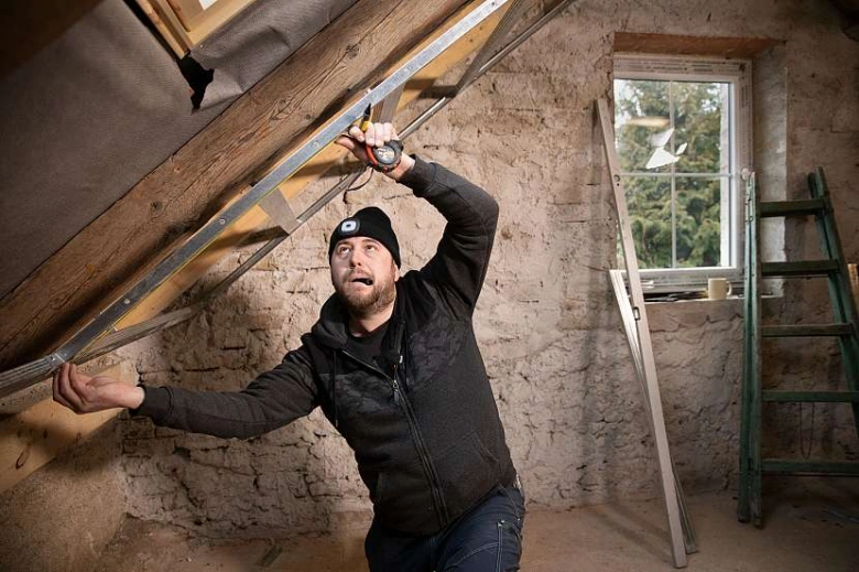 Muž měří podkroví před instalací sádrokartonu