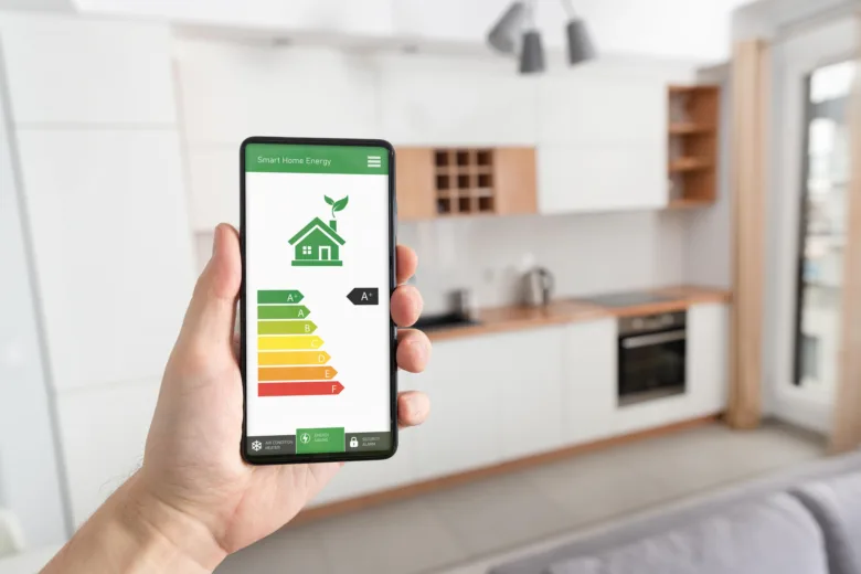 Ruka drží chytrý telefon s aplikací pro sledování spotřeby elektřiny.