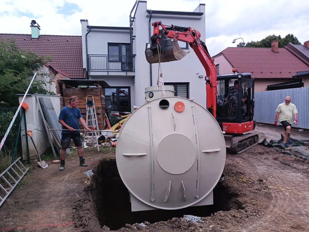Instalace septiku do jámy pomocí výkopového stroje.