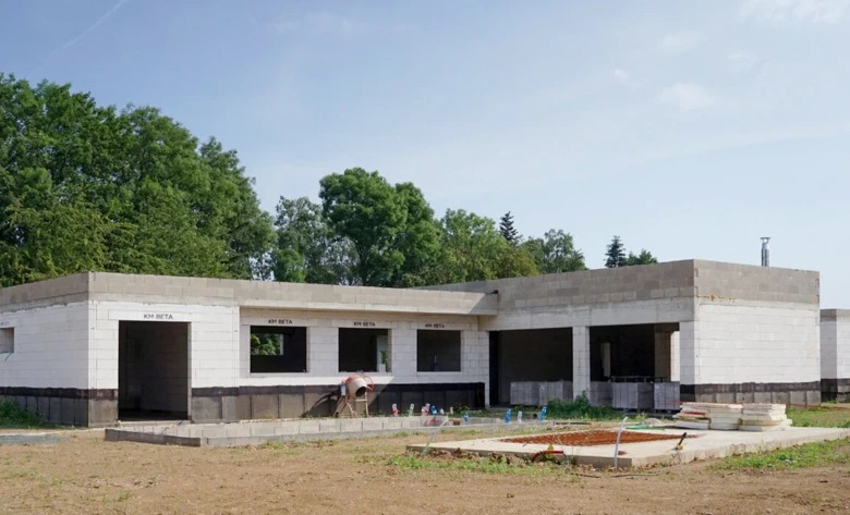 Stavba rodinného domu v fázi hrubé stavby s betonovými bloky a okny bez skel.