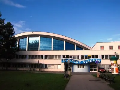 Fotografie plaveckého stadionu v Českých Budějovicích s modrou oblohou.