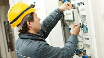 Elektrikář pracuje na rozvaděči pro dálkové ovládání.