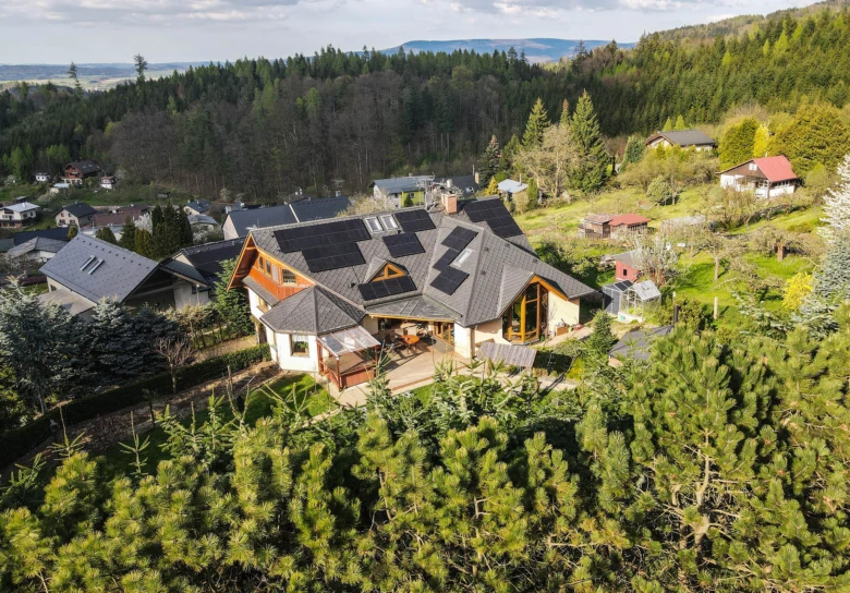 Dům na kopci s fotovoltaickými panely na střeše.