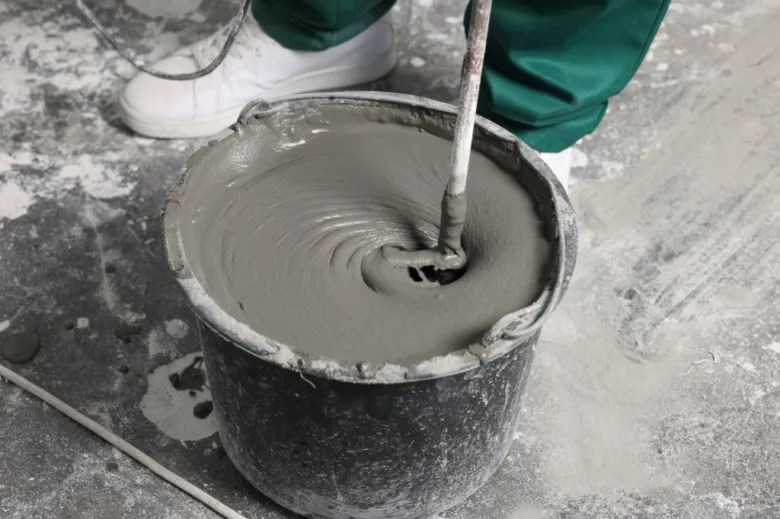 Míchání betonu v kbelíku při betonování podlahy.