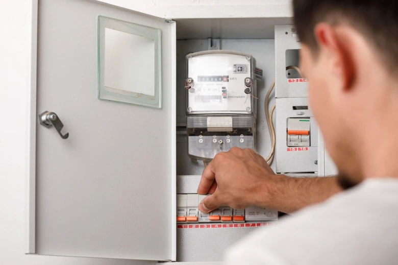 Muž upravuje jistič v elektrickém rozvaděči s měřidlem.