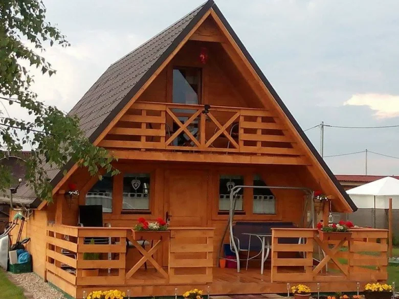 Drevená chata na klíč s terasou a balkónem.