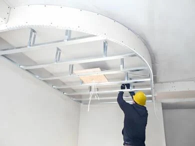 Stavebník montuje rámovou konstrukci pro zakřivený sádrokartonový strop.