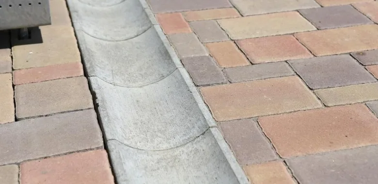 Konkrétní drenážní kanál vedle dlažebního chodníku venku.