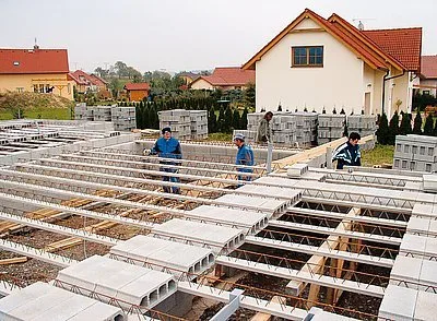 Montáž betonových tvárnic na základě nového domu s dělníky.