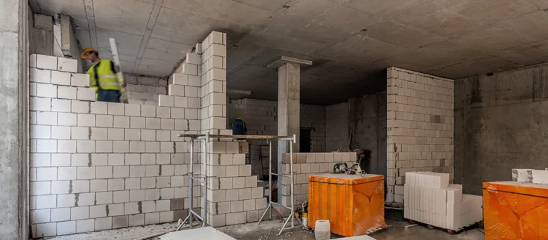 Stavebník montuje betonové tvárnice na stavbě.