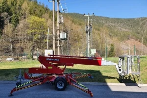 Červená zemědělská technika u elektrických sloupů v přírodě.