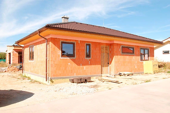 Rodinný dům z porobetonu ve fázi stavby s viditelnými cihlovými stěnami.
