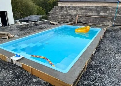 Nově nainstalovaný nadzemní bazén s plavacími hračkami na štěrku.