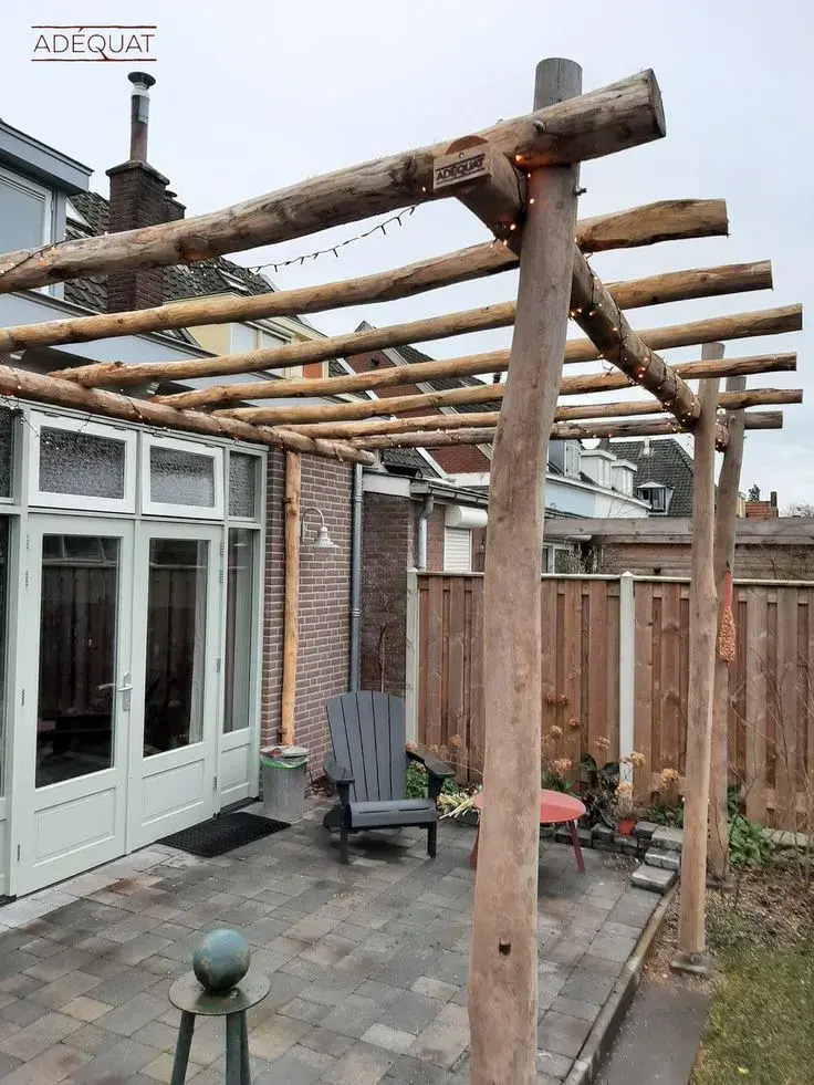 Jednoduchá dřevěná malá pergola na zahradě s lavičkou.