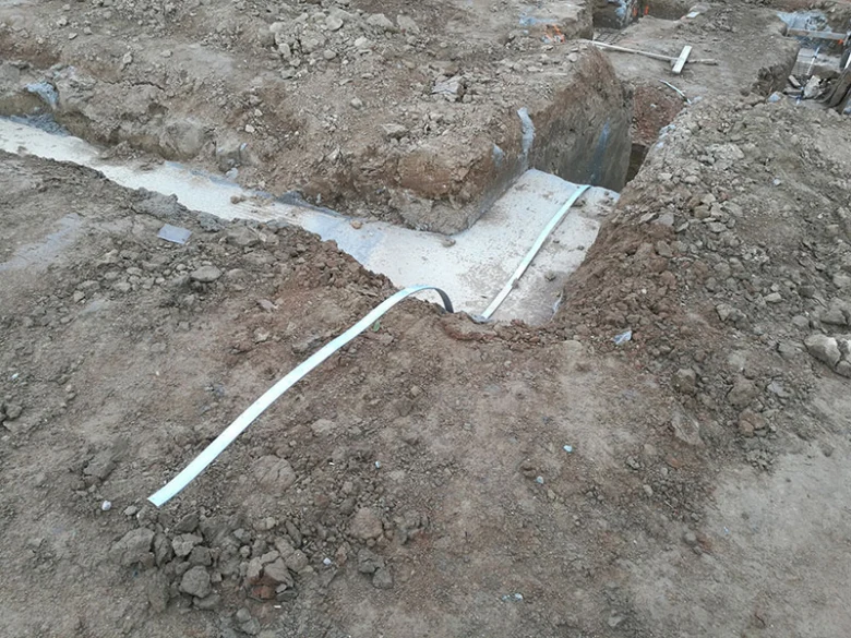 Bílý uzemňovací vodič položený v jámě pro elektroinstalaci.