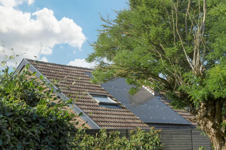 Fotografie střechy domu s fotovoltaickými panely a okny pod širým dnem.