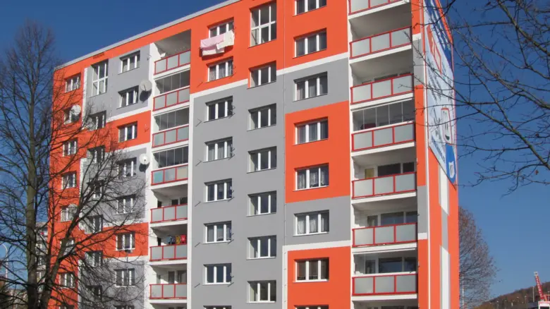 Modernizovaný fasáda bytového domu s oranžovou barvou.